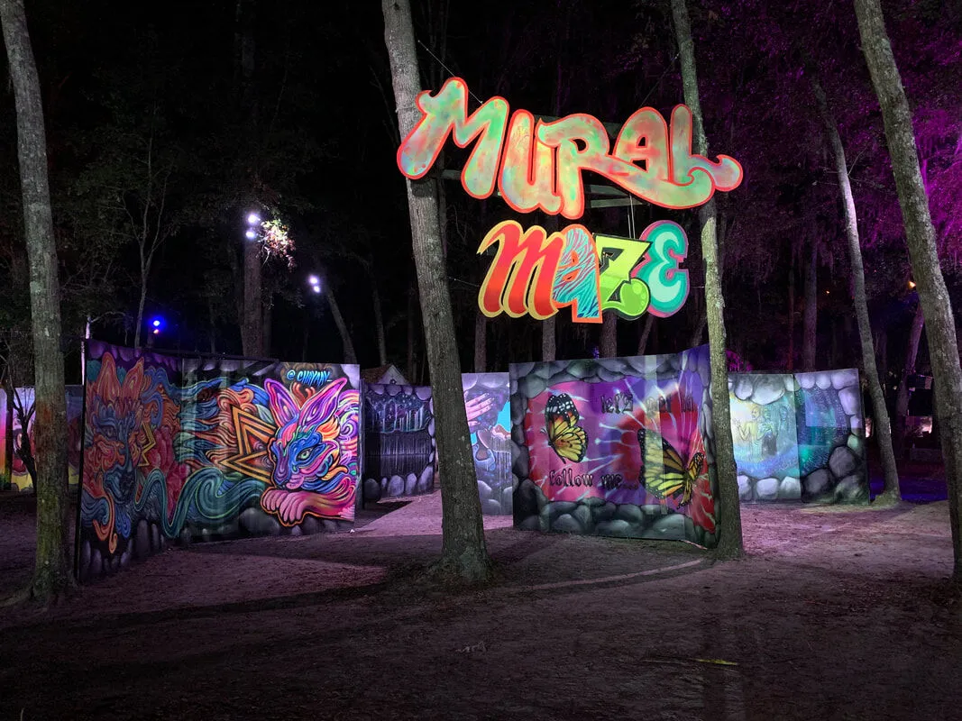 The Mural Maze at night, glowing murals among the trees
