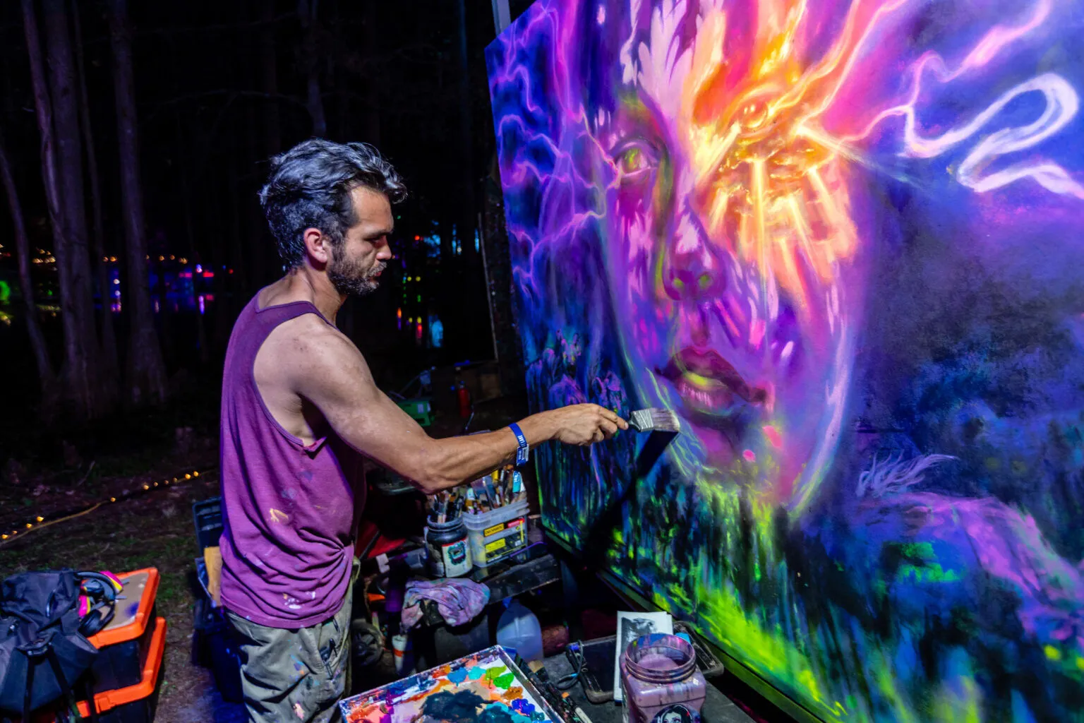 An artist live painting a glowing mural at night
